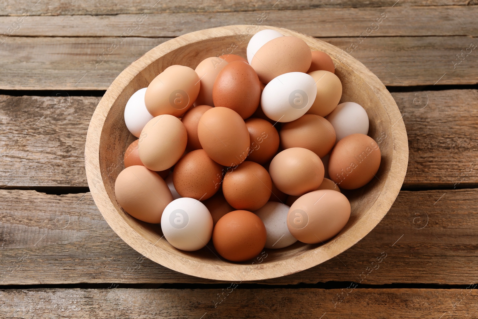 Photo of Chicken eggs in bowl on wooden table