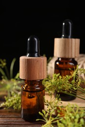 Bottle of essential oil and fresh dill on wooden table, closeup