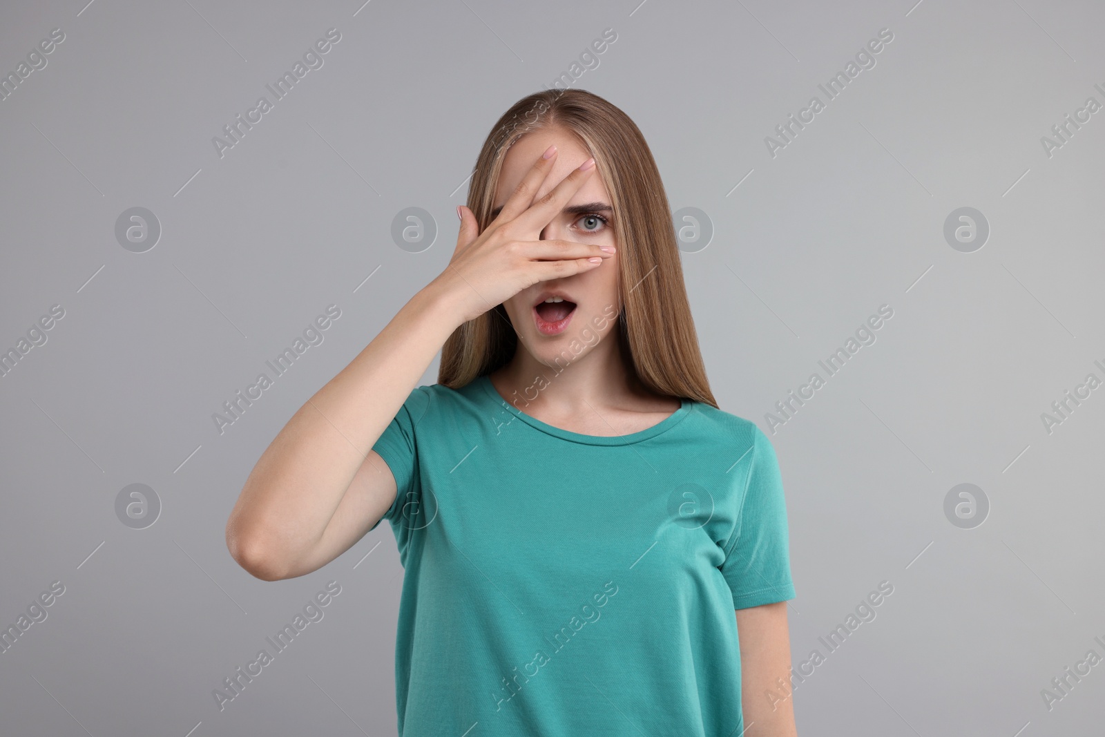 Photo of Embarrassed woman covering face with hand on grey background