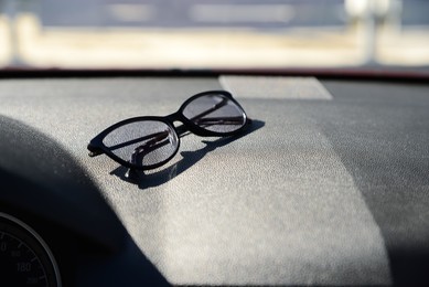 Photo of Stylish glasses on dashboard in car, space for text