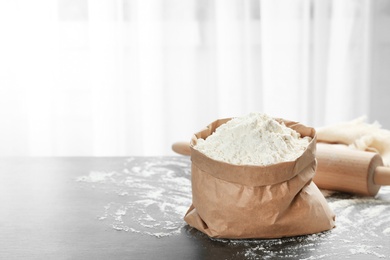 Photo of Paper bag with flour on kitchen table