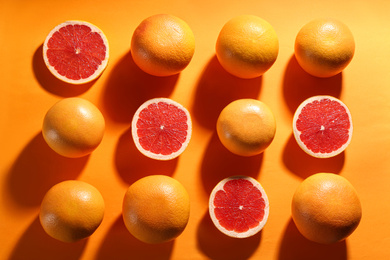 Cut and whole ripe grapefruits on orange background, flat lay