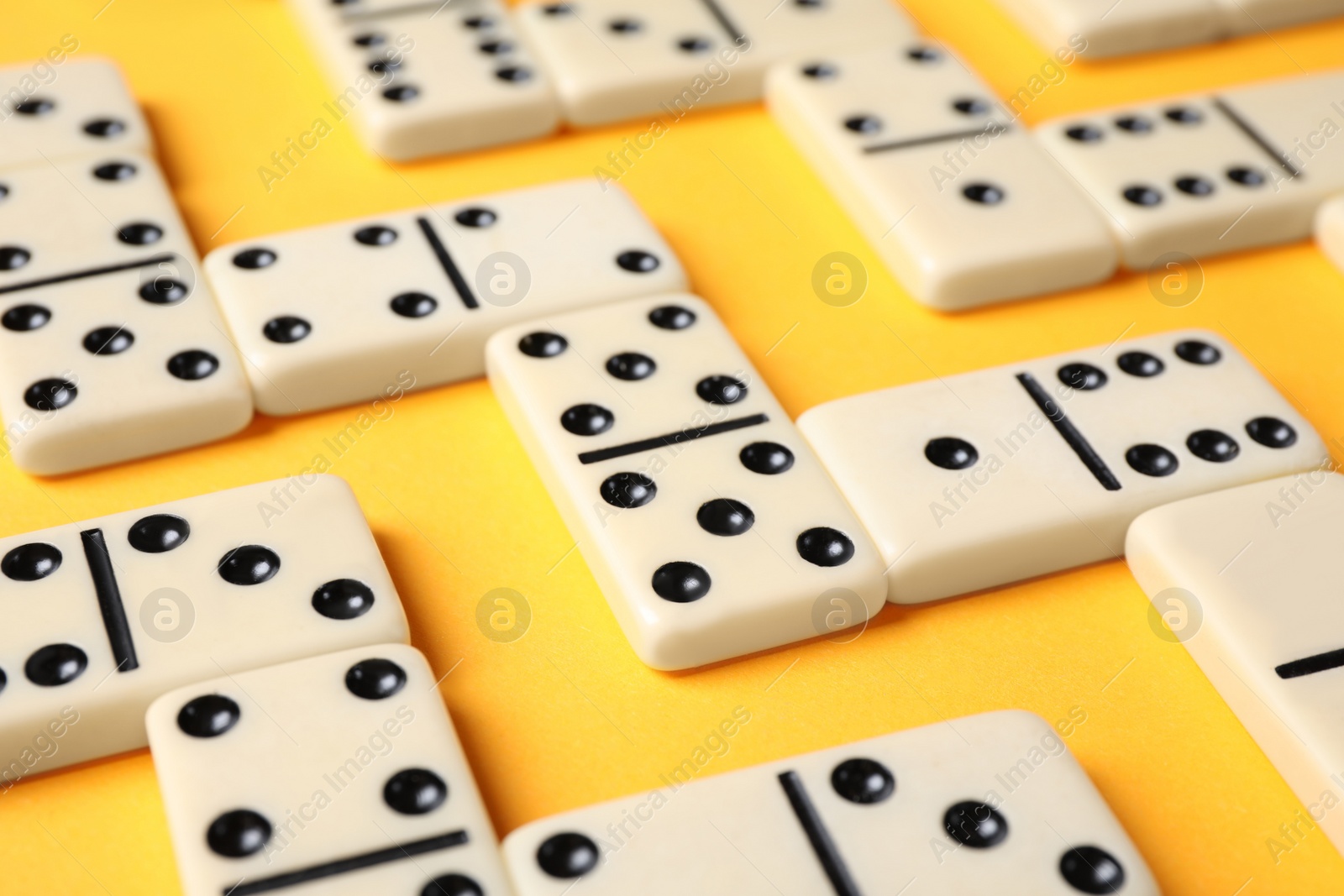 Photo of Classic domino tiles on yellow background, closeup
