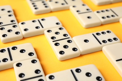 Photo of Classic domino tiles on yellow background, closeup