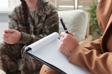 Photo of Psychologist working with military officer in office, focus on hand