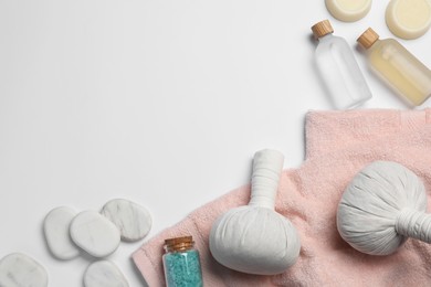 Flat lay composition with herbal massage bags and other spa products on white background, space for text