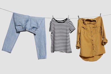 Photo of Different clothes drying on laundry line against light background