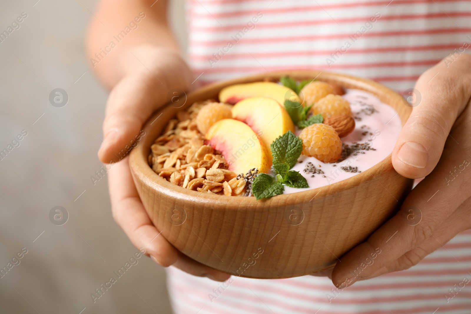 Photo of Woman holding bowl of tasty homemade granola with yogurt, closeup. Healthy breakfast