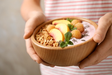 Woman holding bowl of tasty homemade granola with yogurt, closeup. Healthy breakfast