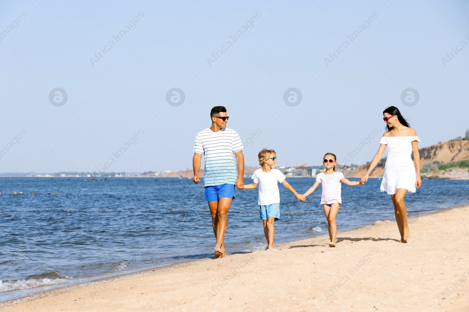 Photo of Happy family walking on sandy beach near sea. Summer holidays