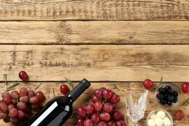Flat lay composition with red wine and snacks on wooden table, space for text