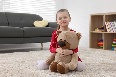 Cute little girl playing with teddy bear at home