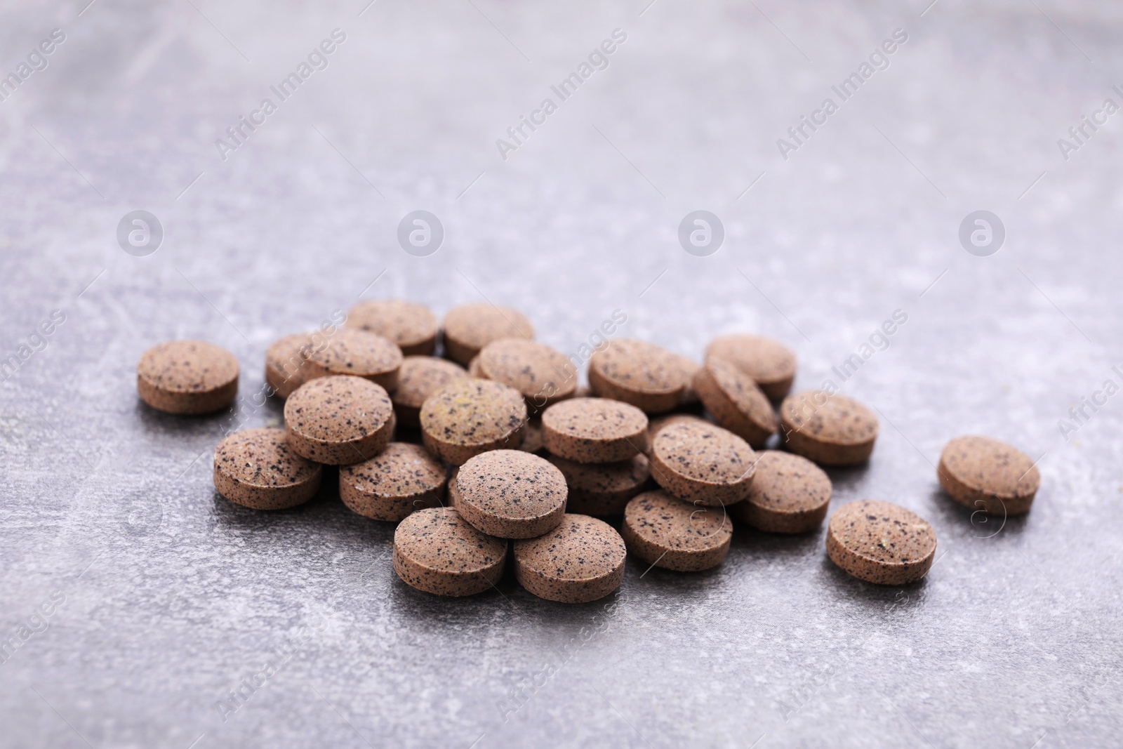 Photo of Heap of brewer's yeast tablets on grey table, closeup