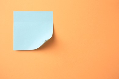 Photo of Blank paper note on pale orange background, top view. Space for text