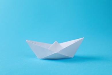 Photo of Handmade white paper boat on light blue background. Origami art