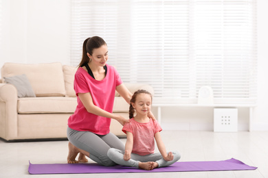 Photo of Young mother with little daughter practicing yoga at home