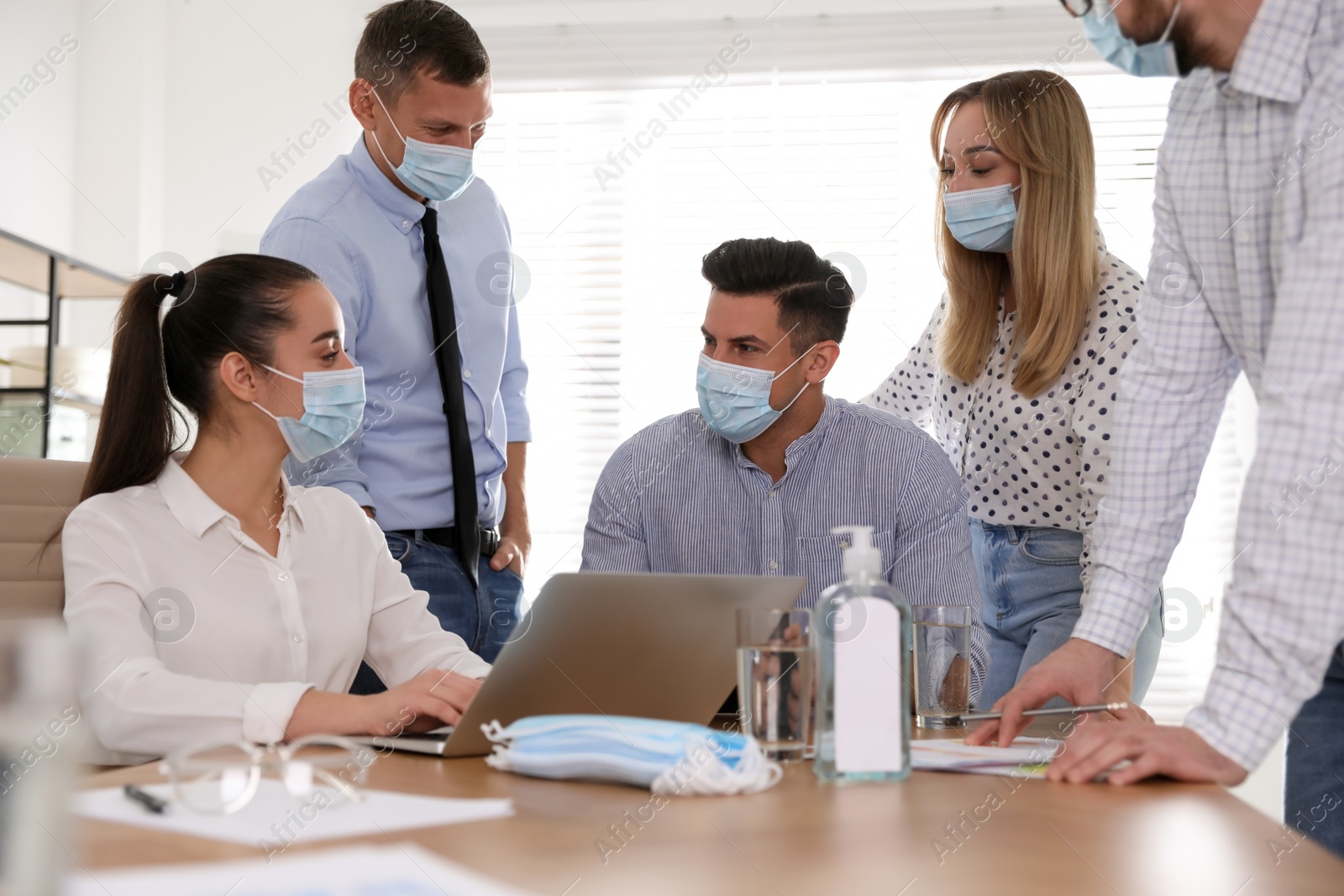 Photo of Group of coworkers with protective masks in office. Business meeting during COVID-19 pandemic