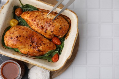 Photo of Baked chicken fillets with vegetables and marinade on white tiled table, flat lay. Space for text