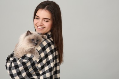 Photo of Happy woman with her cute cat on light grey background, space for text