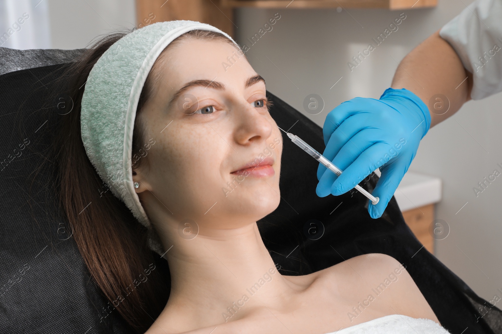 Photo of Cosmetologist giving facial injection to patient in clinic, closeup. Cosmetic surgery