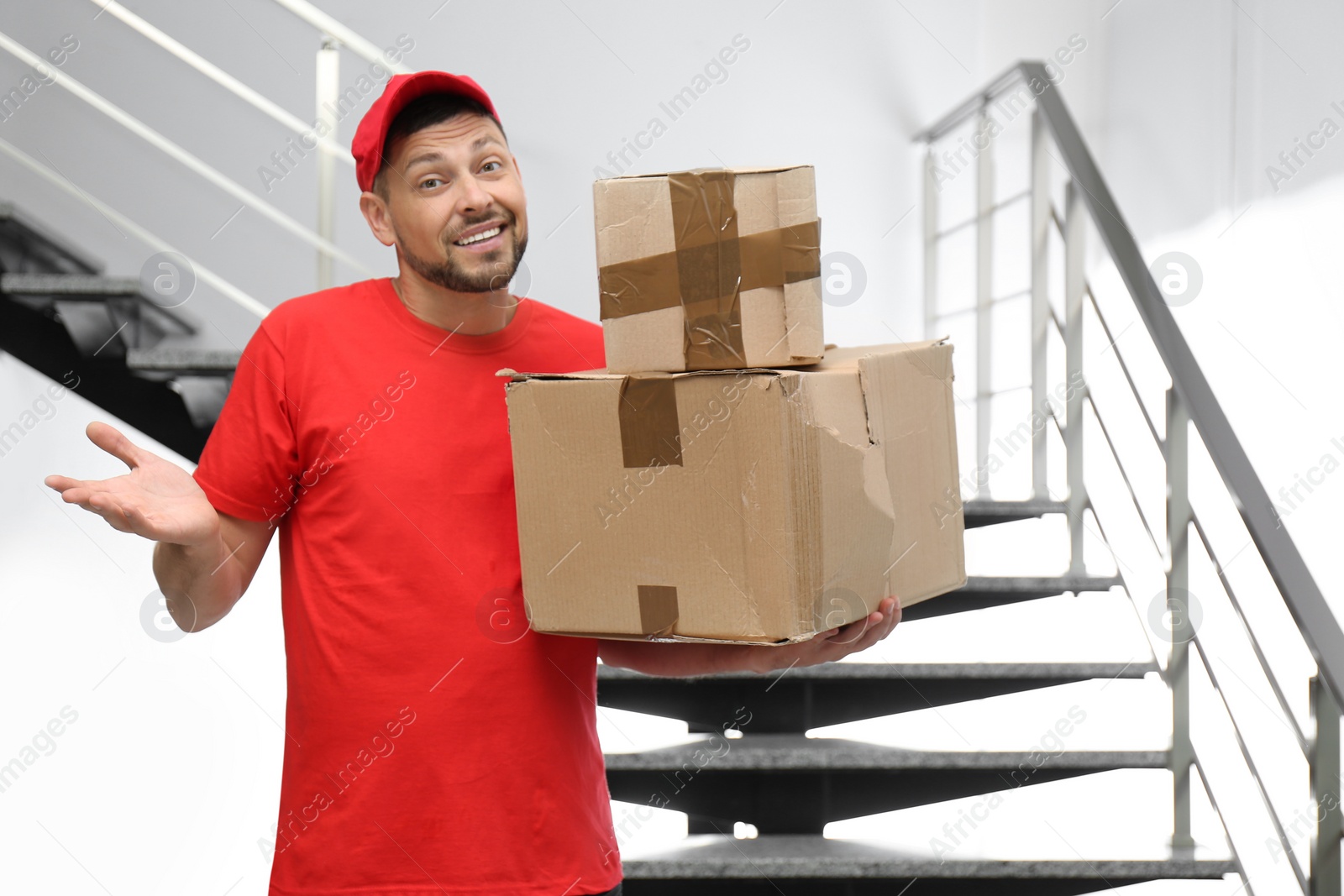 Photo of Emotional courier with damaged cardboard boxes indoors. Poor quality delivery service