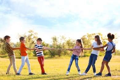 Cute little children playing with rope outdoors on sunny day