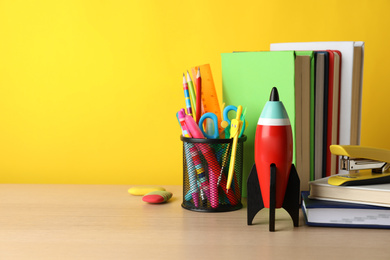 Bright toy rocket and school supplies on wooden table. Space for text