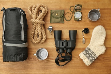 Photo of Flat lay composition with sleeping bag and camping equipment on wooden background