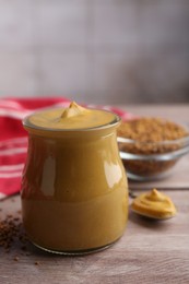 Photo of Tasty mustard sauce in jar on wooden table, closeup