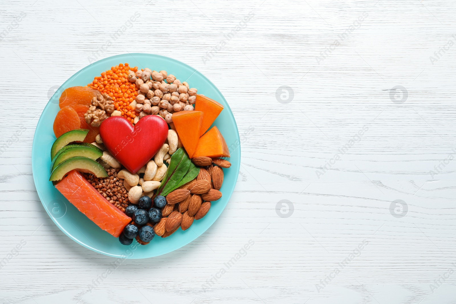 Photo of Plate with heart-healthy products on wooden background, top view. Space for text