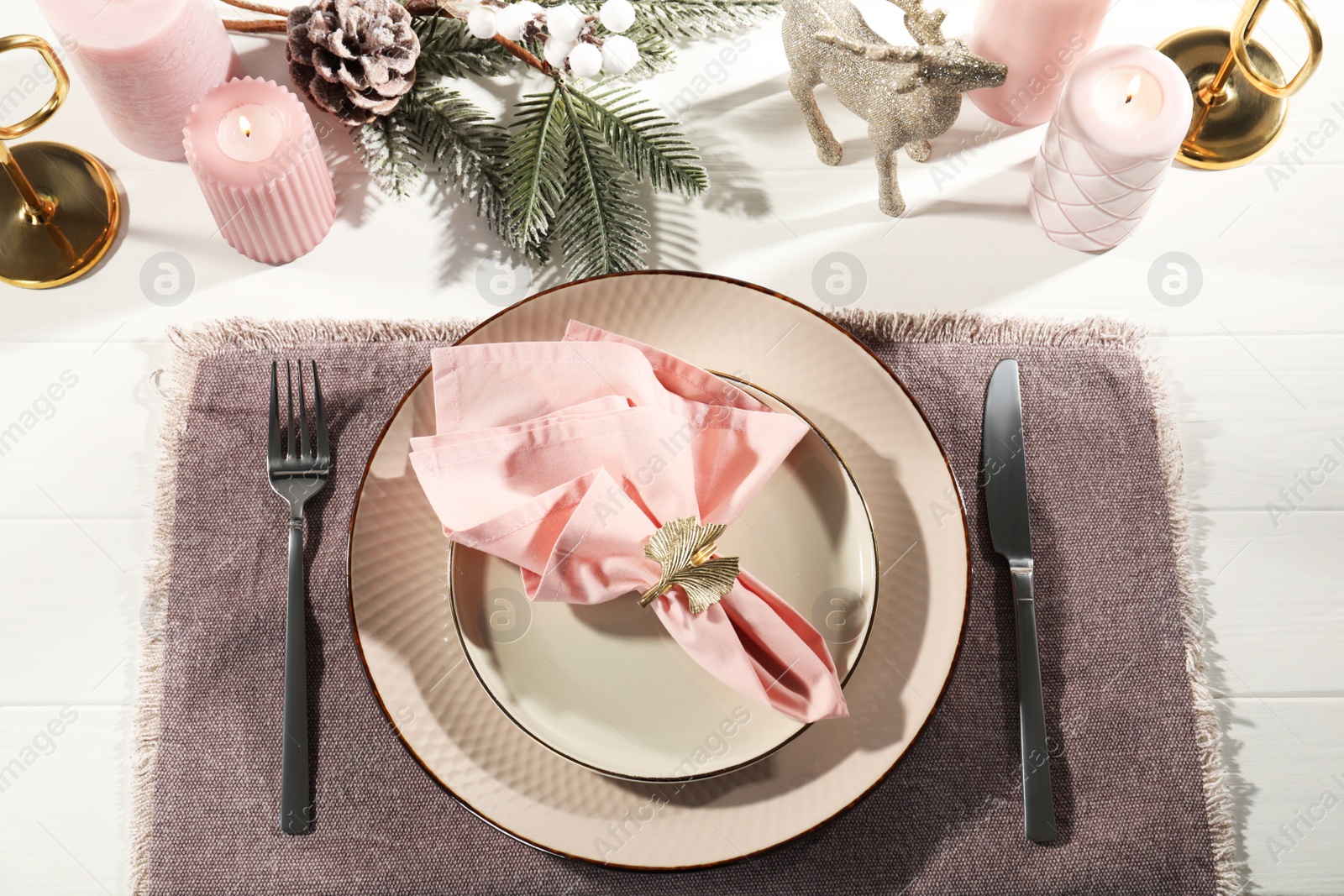 Photo of Stylish table setting with pink fabric napkin, beautiful decorative ring and festive decor on white wooden background, flat lay