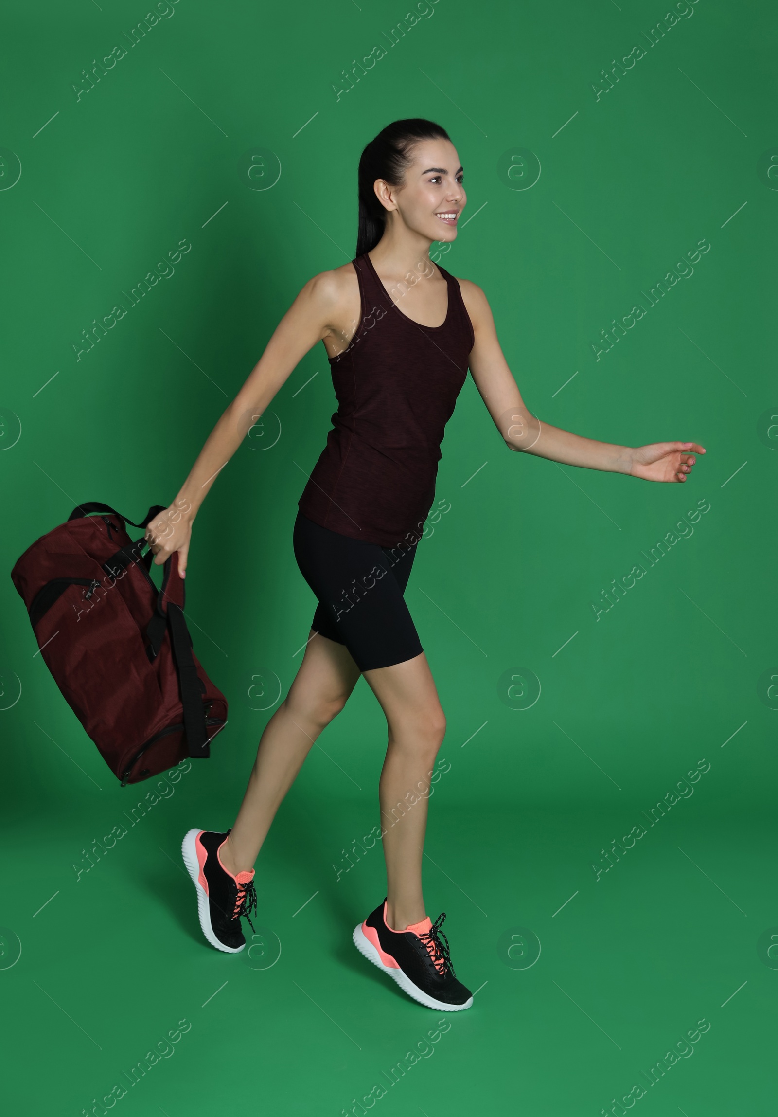 Photo of Beautiful woman with sports bag on green background