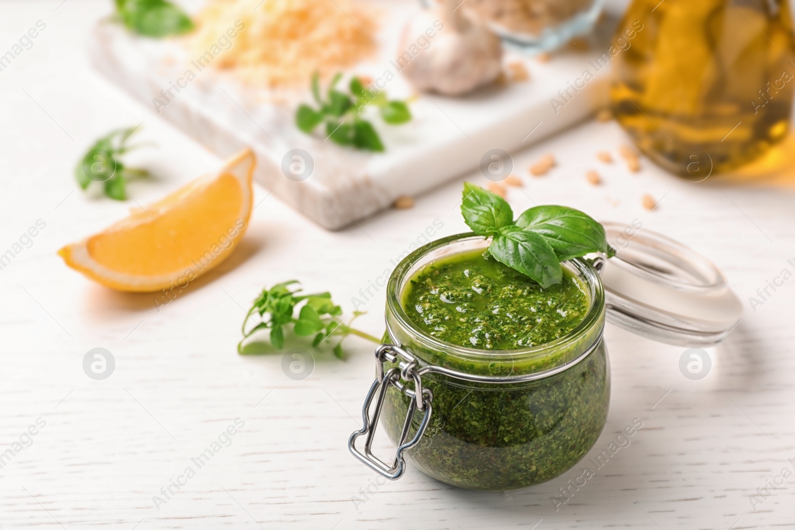 Photo of Composition with homemade basil pesto sauce in glass jar on table