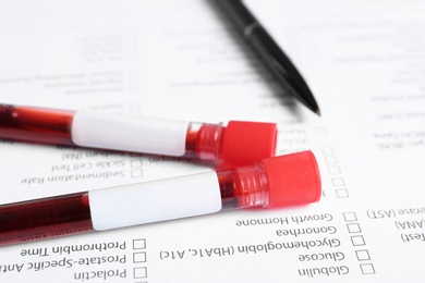 Test tubes with blood samples for analysis on laboratory test form, closeup