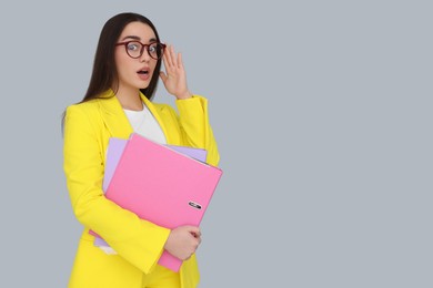 Photo of Young female intern with eyeglasses and folders on grey background, space for text