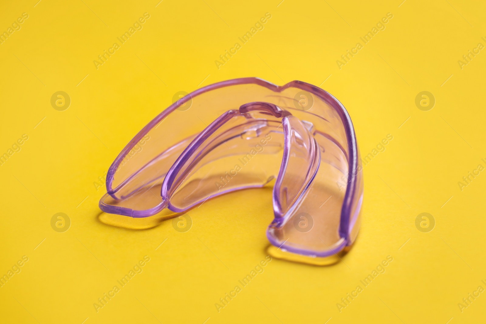 Photo of Dental mouth guard on yellow background, closeup. Bite correction