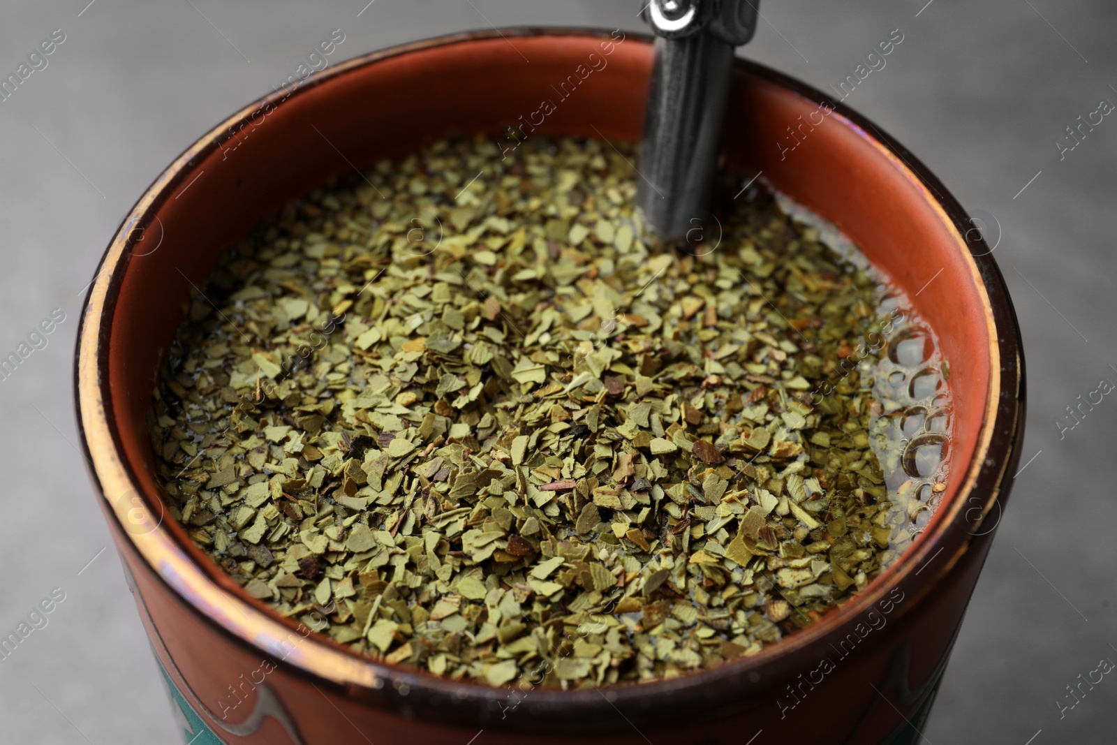 Photo of Guampa with bombilla and mate tea on grey table, closeup