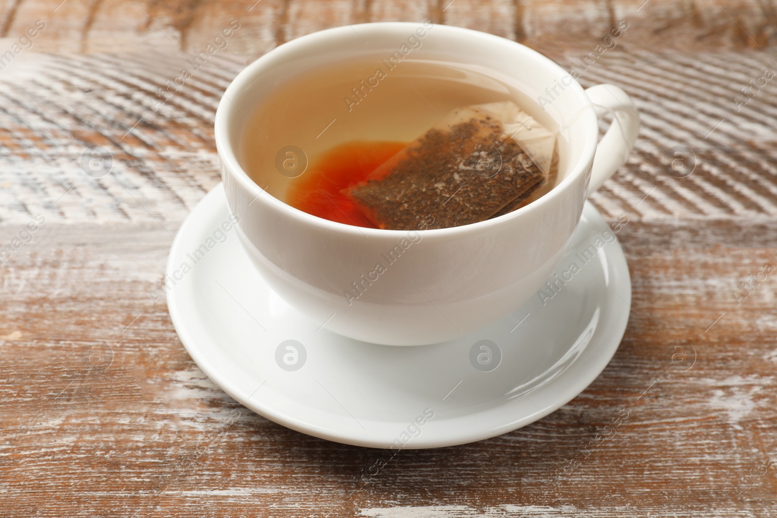 Photo of Tea bag in cup with hot drink on wooden rustic table, closeup