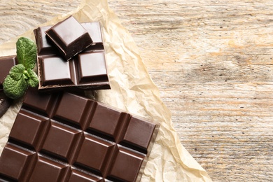 Photo of Tasty chocolate on wooden background, flat lay. Space for text