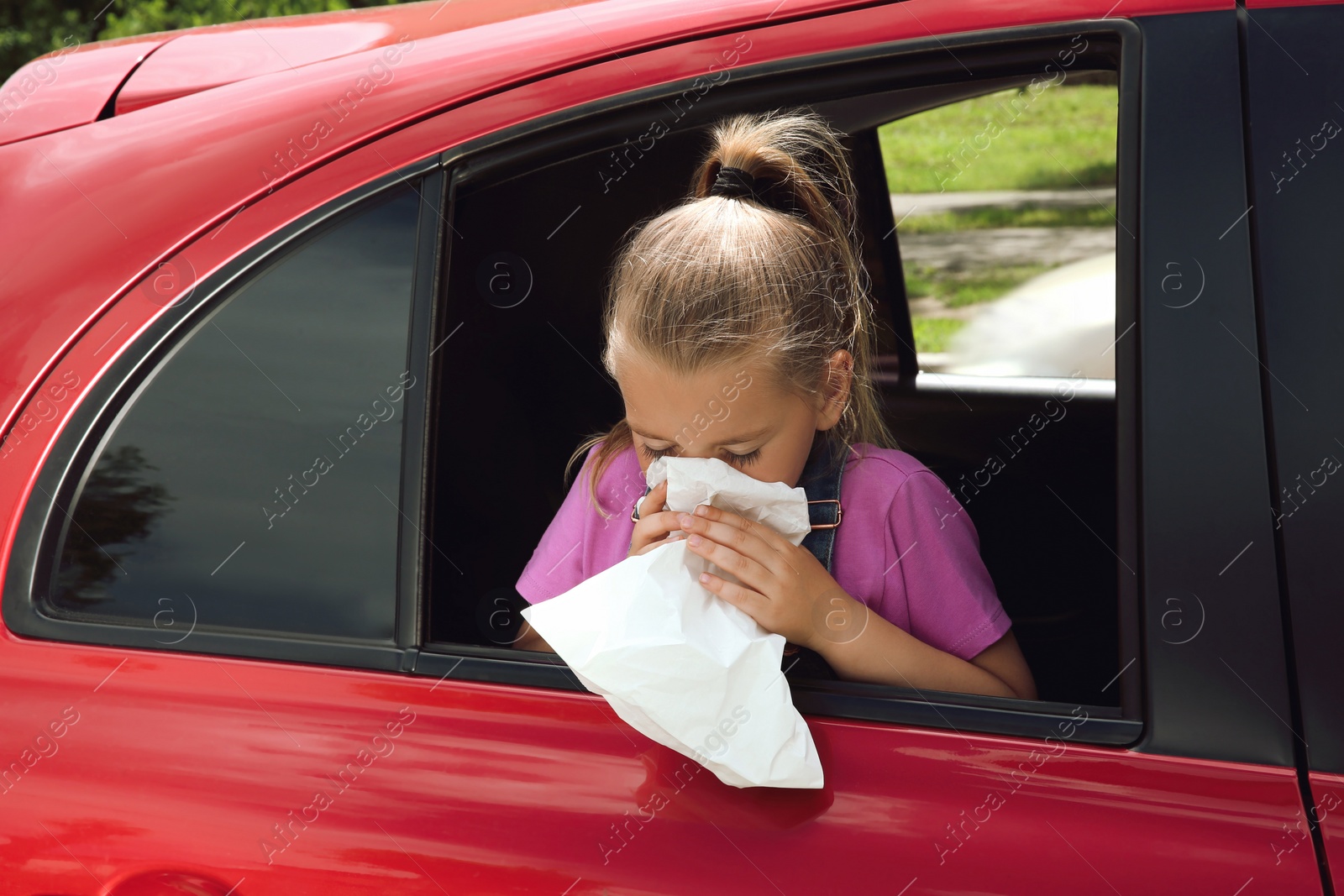 Photo of Little girl with paper bag suffering from nausea in car