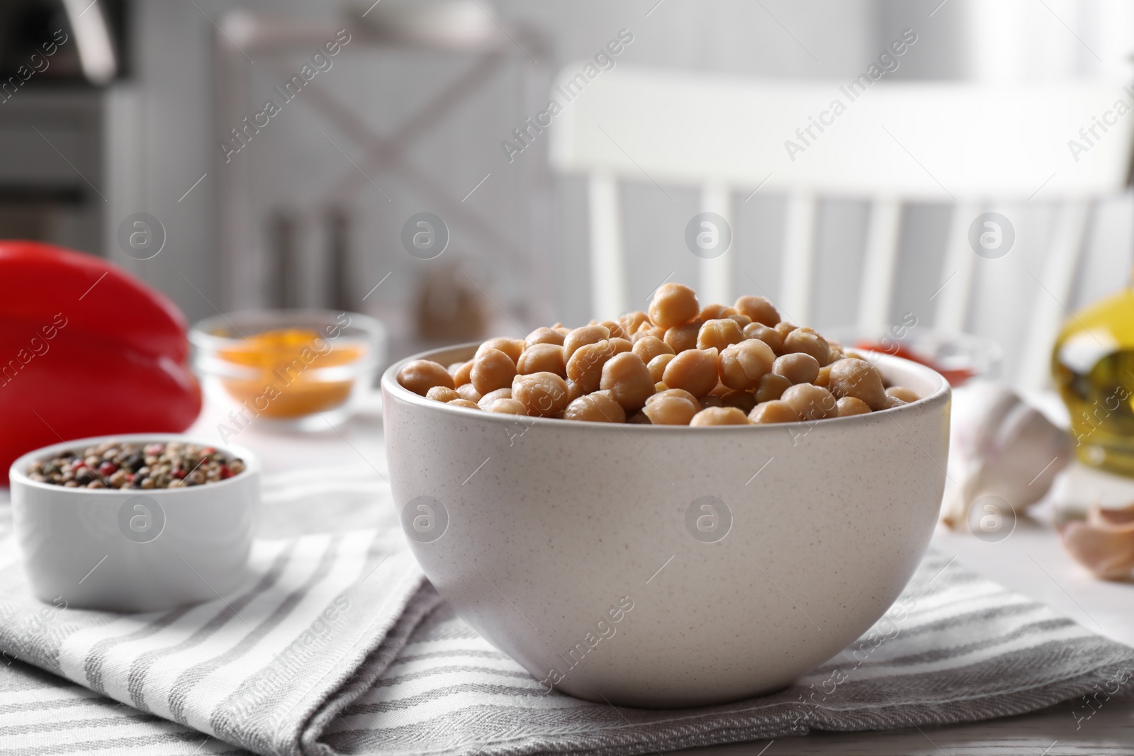 Photo of Bowl with delicious chickpeas on table in kitchen