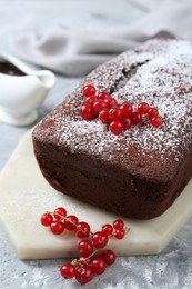 Photo of Tasty chocolate sponge cake with powdered sugar and currant on light grey textured table, closeup