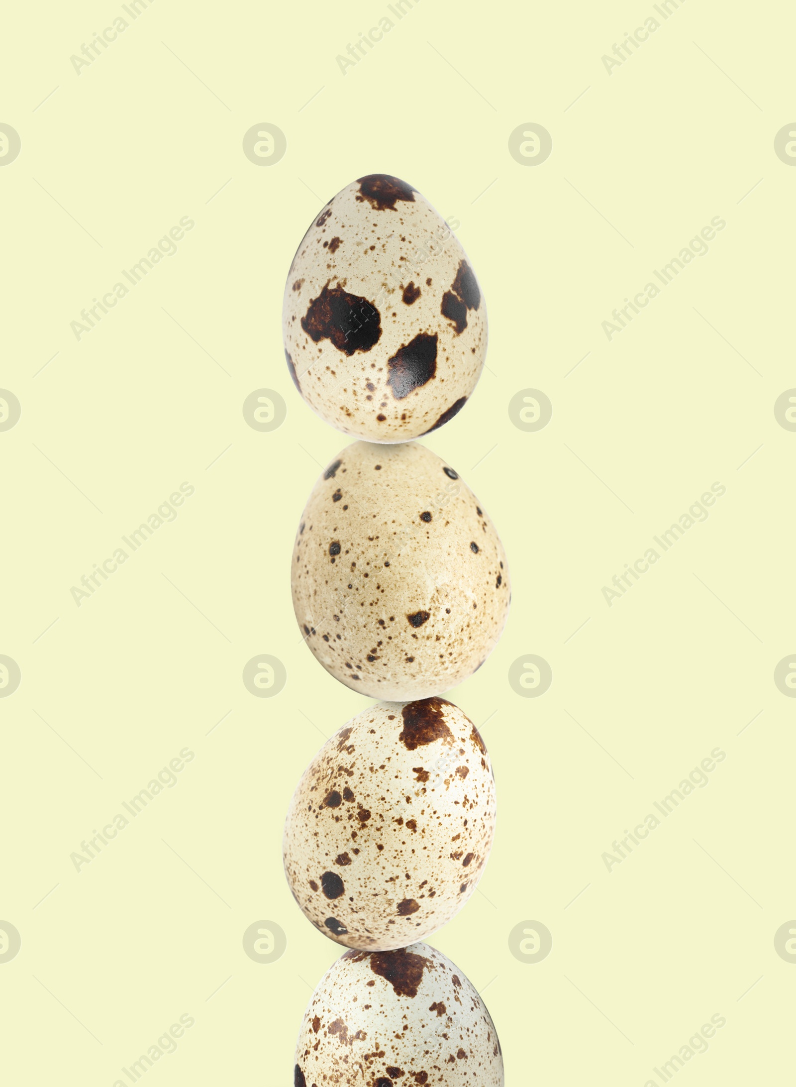 Image of Stacked speckled quail eggs on light beige background