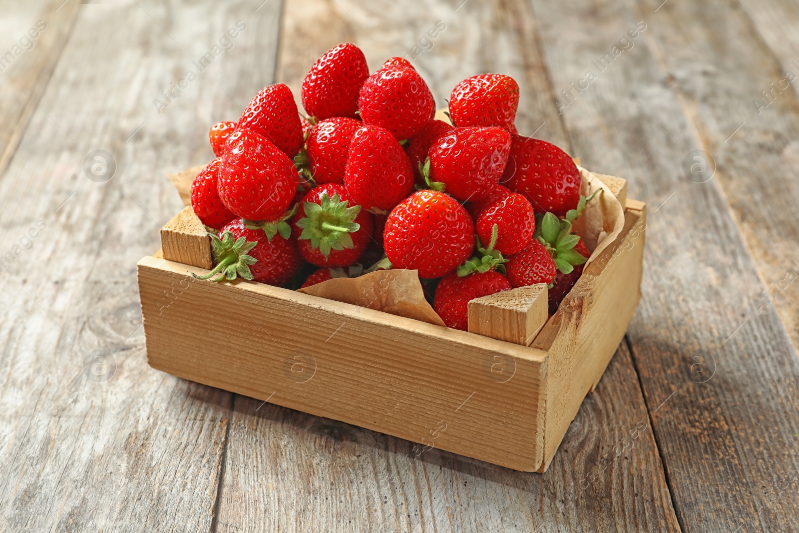 Photo of Crate with ripe strawberries on wooden background