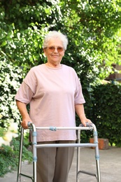 Elderly woman using walking frame in park