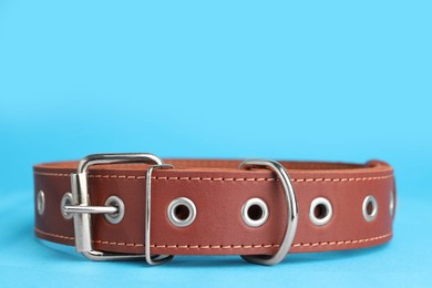 Photo of Brown leather dog collar on light blue background, closeup. Space for text