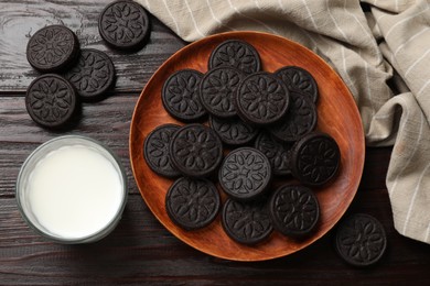 Photo of Plate with tasty sandwich cookies and milk on wooden table, flat lay