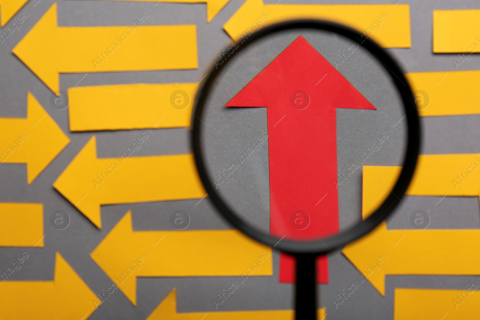 Photo of Recruitment process, searching for employee. View through magnifying glass of red paper arrow among yellow ones on grey background, flat lay