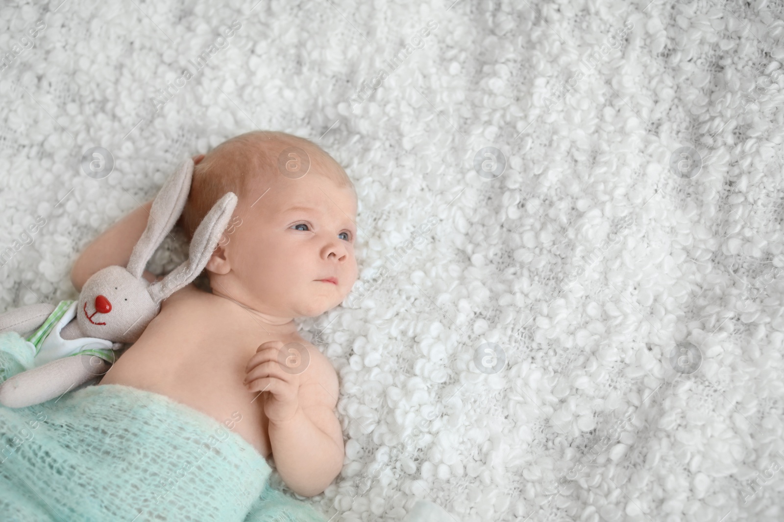 Photo of Adorable newborn baby with toy bunny on bed, top view