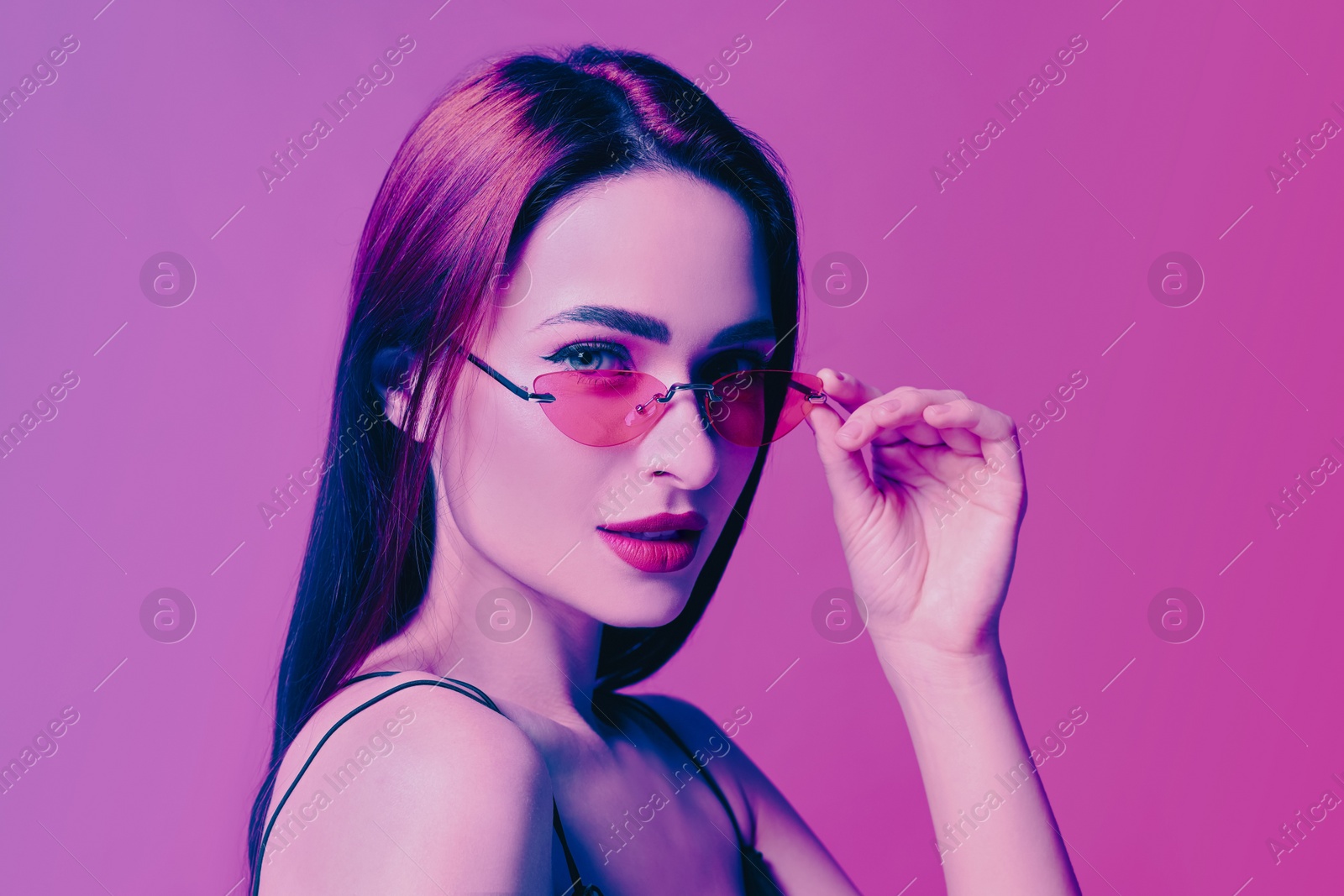 Image of Portrait of beautiful woman with sunglasses in neon lights